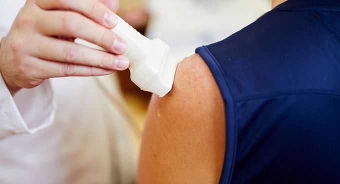 Arzt untersucht die Schulter eines Patienten mit Ultraschall