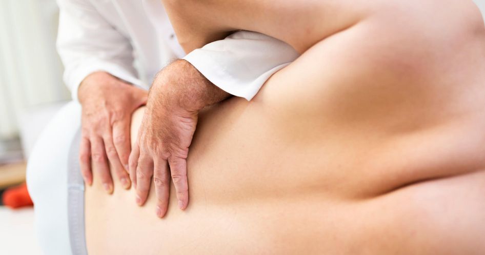 Arzt massiert Rücken eines Patienten bei der manuellen Therapie