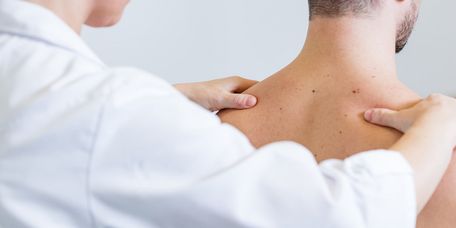 Arzt prüft Rücken des Patienten