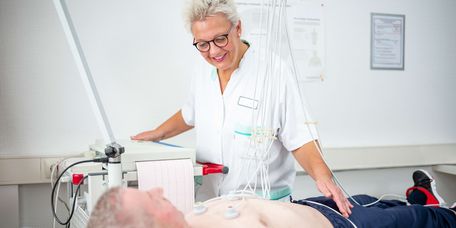 Pflegekraft bereitet Patienten auf EKG vor